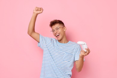 Happy young man with controller on pink background