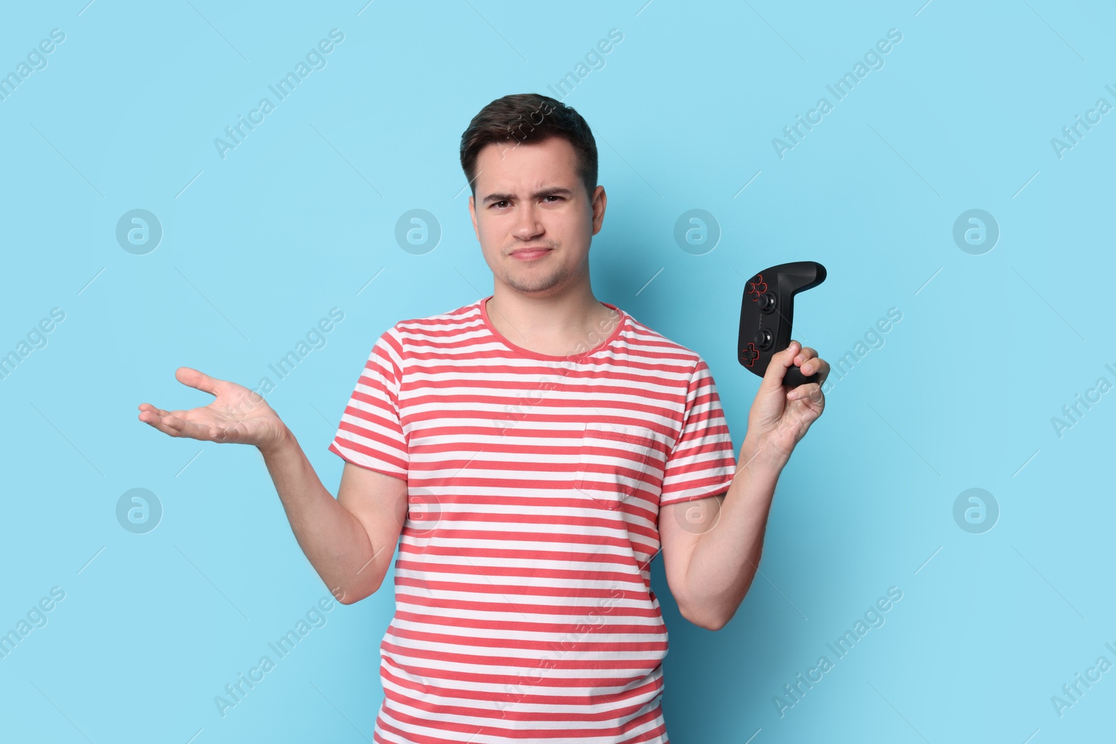 Photo of Young man with controller on light blue background