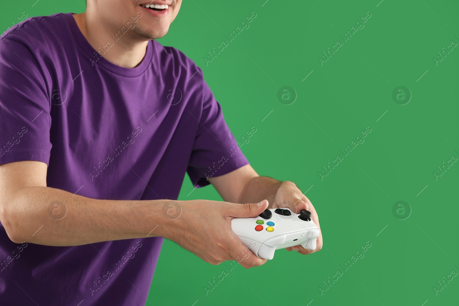 Photo of Man playing video games with controller on green background, closeup. Space for text