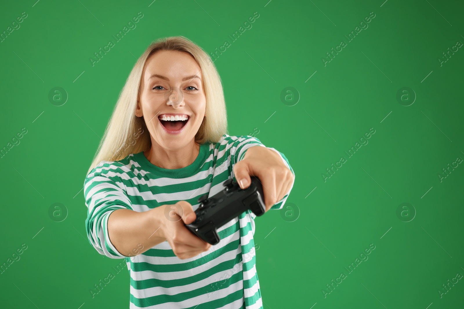 Photo of Happy woman playing video games with controller on green background, space for text