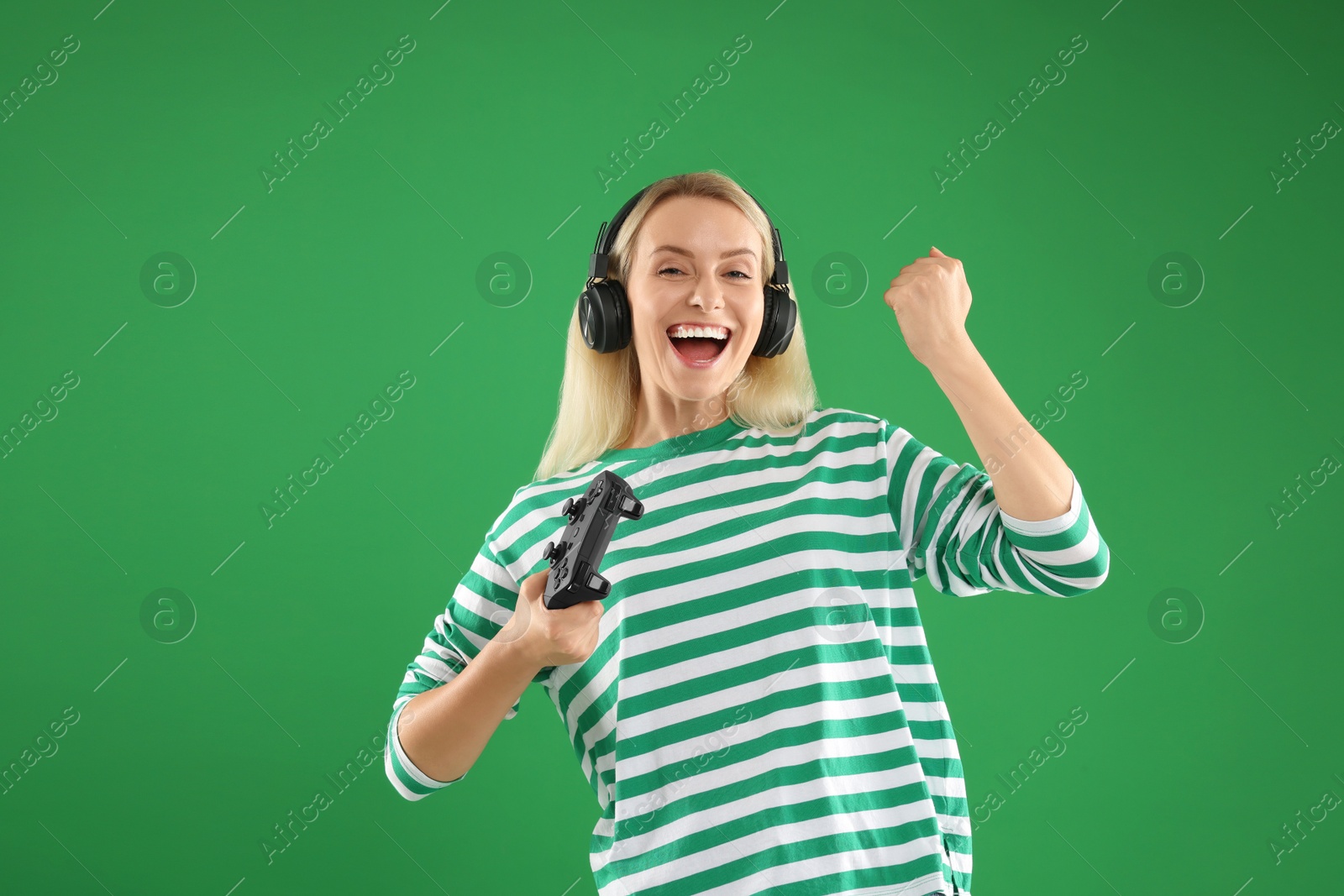 Photo of Happy woman in headphones with controller on green background