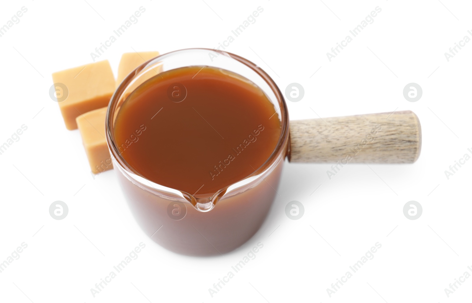 Photo of Tasty caramel sauce in glass measuring cup and sweet candies isolated on white