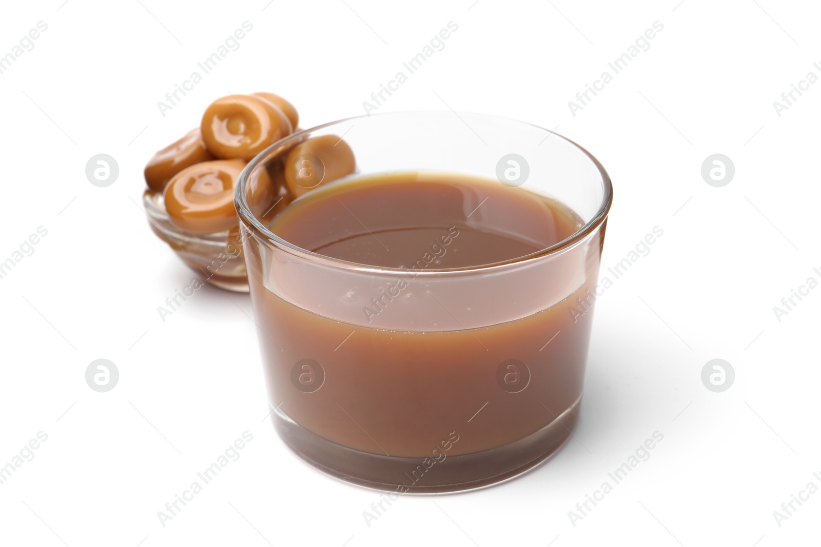 Photo of Tasty caramel sauce in glass bowl and candies isolated on white