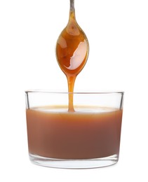 Photo of Tasty caramel sauce dripping from spoon into glass bowl on white background, closeup