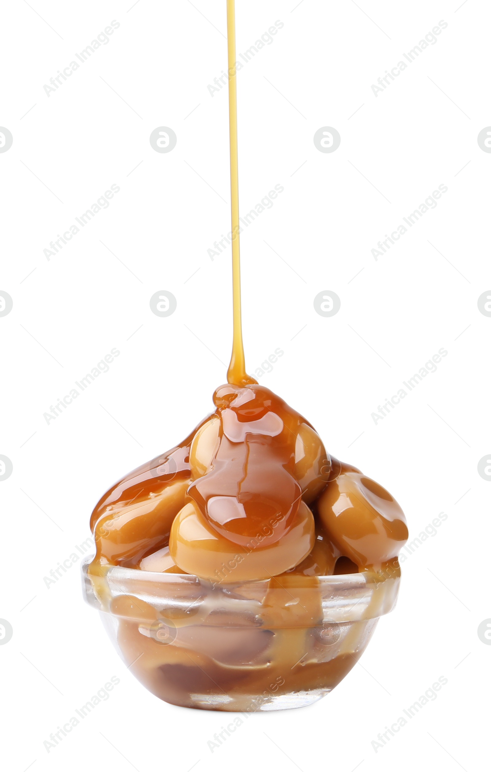 Photo of Caramel sauce dripping onto candies on white background, closeup