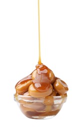 Photo of Caramel sauce dripping onto candies on white background, closeup