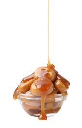 Photo of Caramel sauce dripping onto candies on white background, closeup