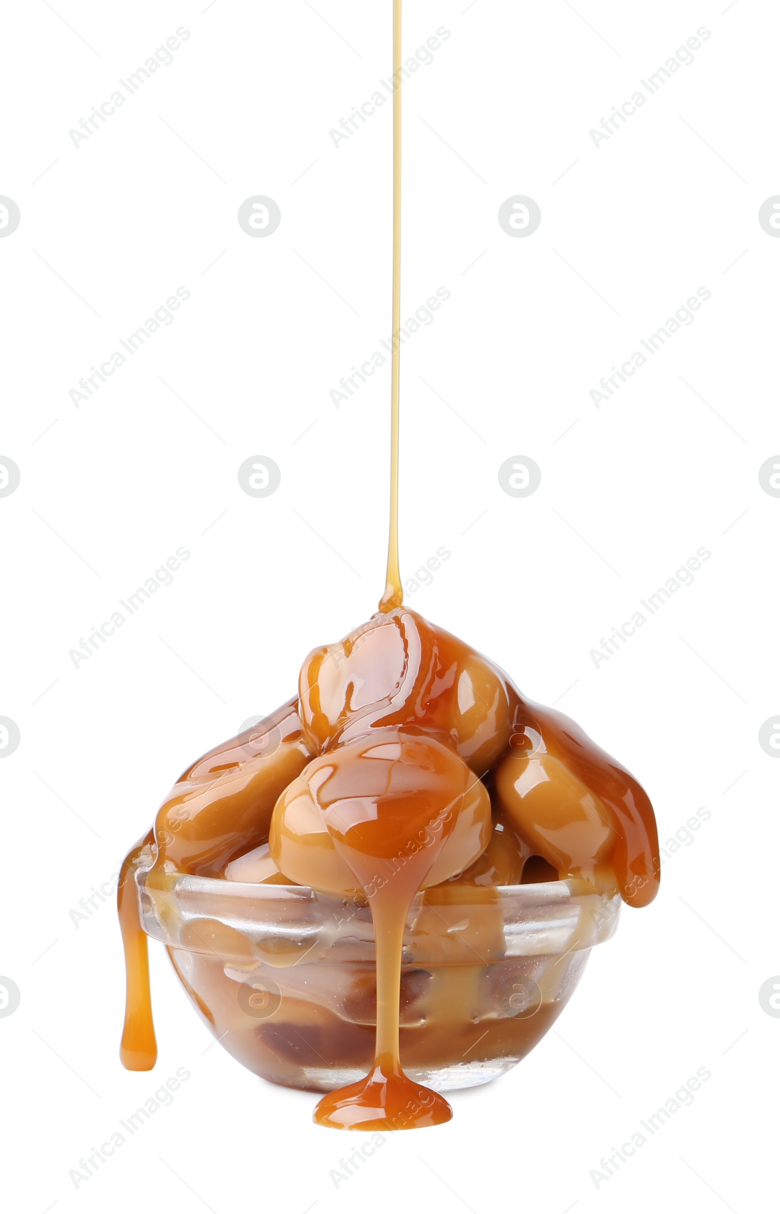 Photo of Caramel sauce dripping onto candies on white background, closeup