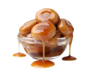 Photo of Tasty candies with caramel sauce in glass bowl isolated on white