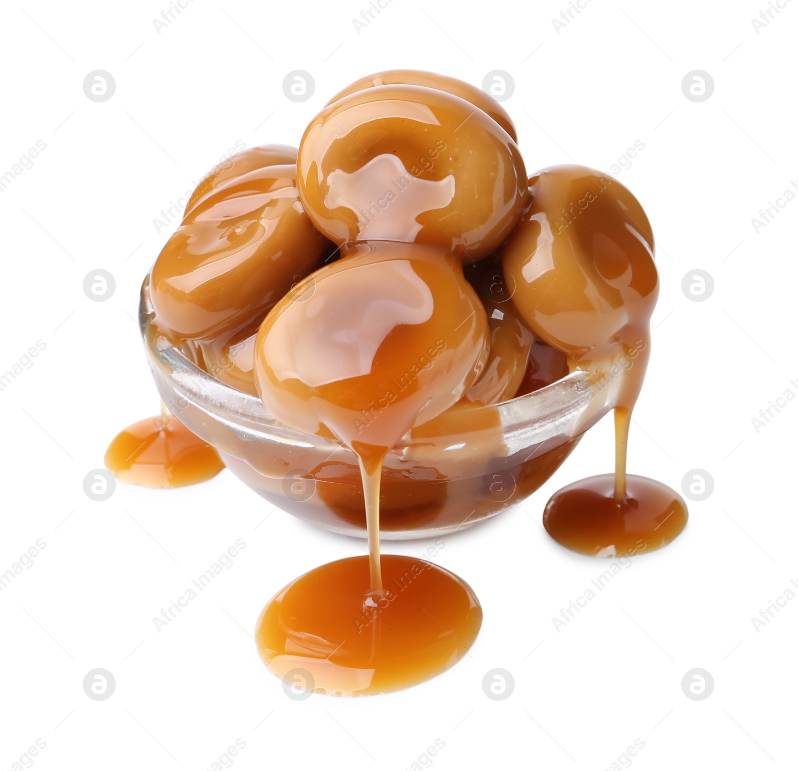 Photo of Tasty candies with caramel sauce in glass bowl isolated on white