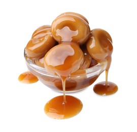 Photo of Tasty candies with caramel sauce in glass bowl isolated on white