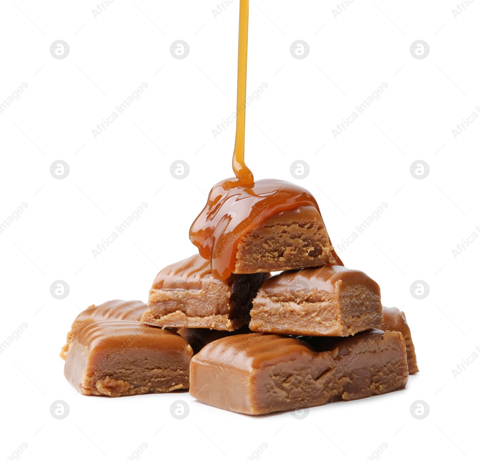 Photo of Caramel sauce dripping onto candies on white background, closeup