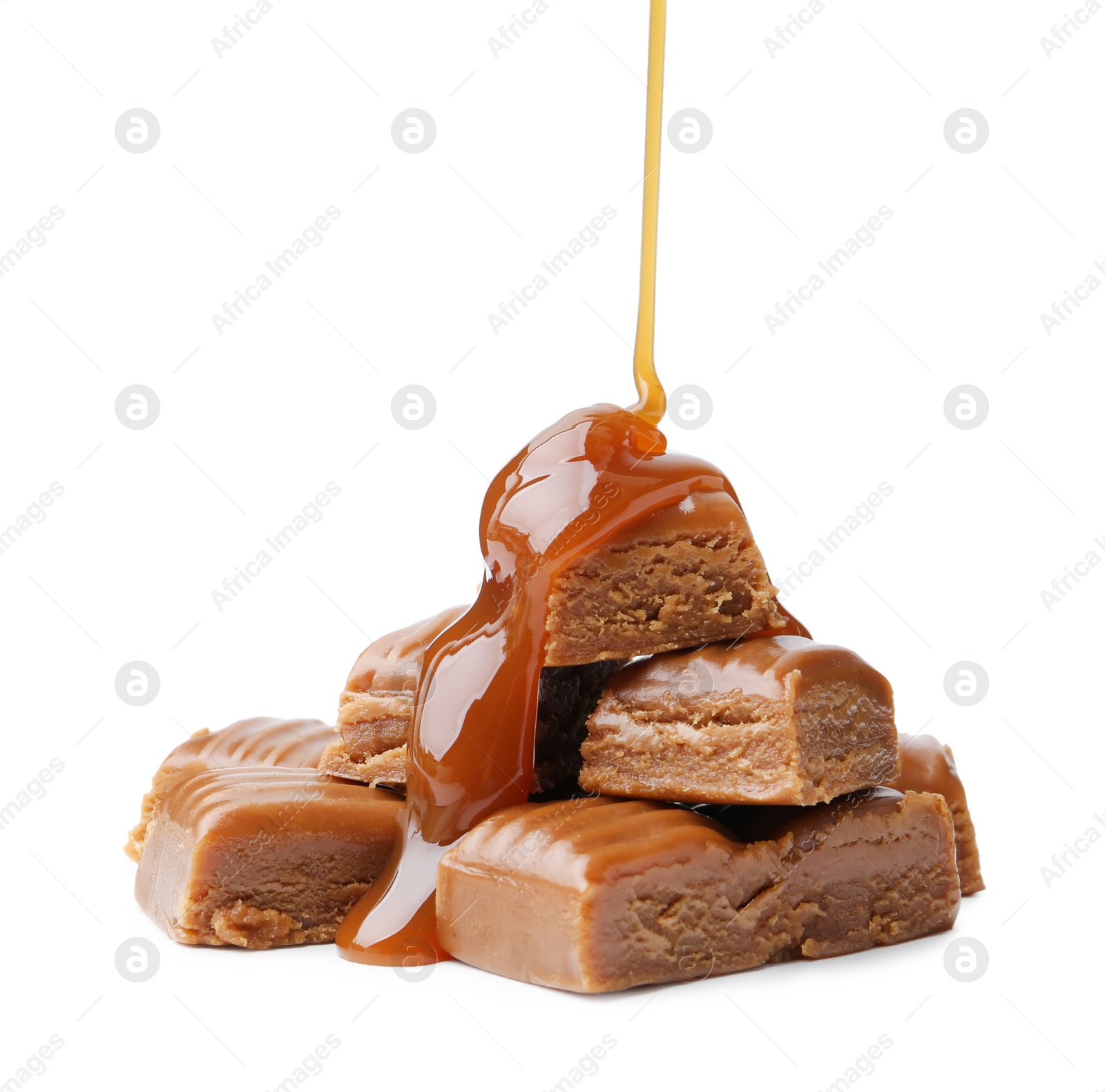 Photo of Caramel sauce dripping onto candies on white background, closeup