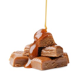 Photo of Caramel sauce dripping onto candies on white background, closeup