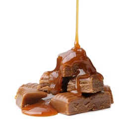 Photo of Caramel sauce dripping onto candies on white background, closeup