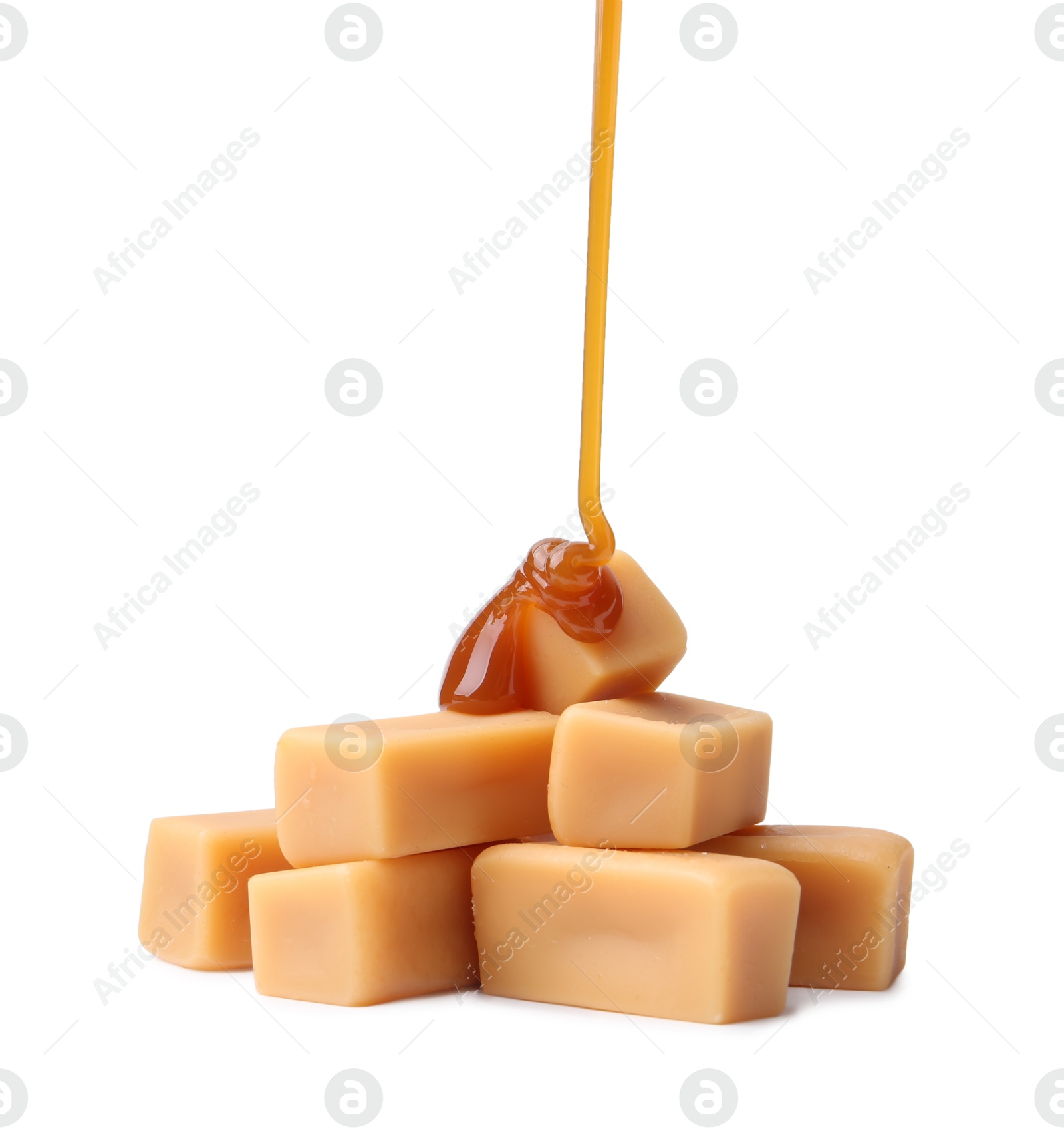 Photo of Caramel sauce dripping onto candies on white background, closeup