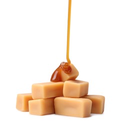 Photo of Caramel sauce dripping onto candies on white background, closeup