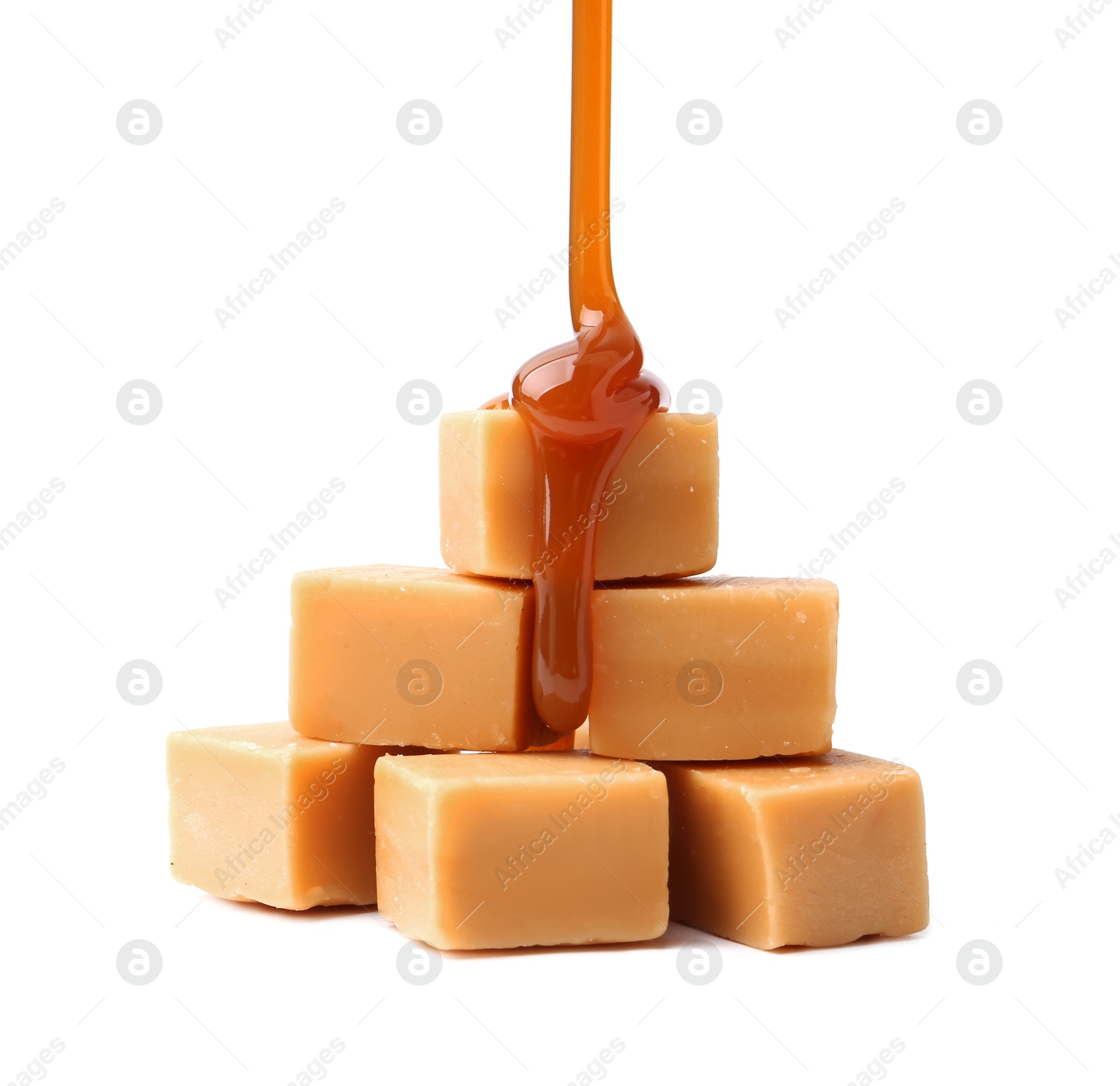 Photo of Caramel sauce dripping onto candies on white background, closeup