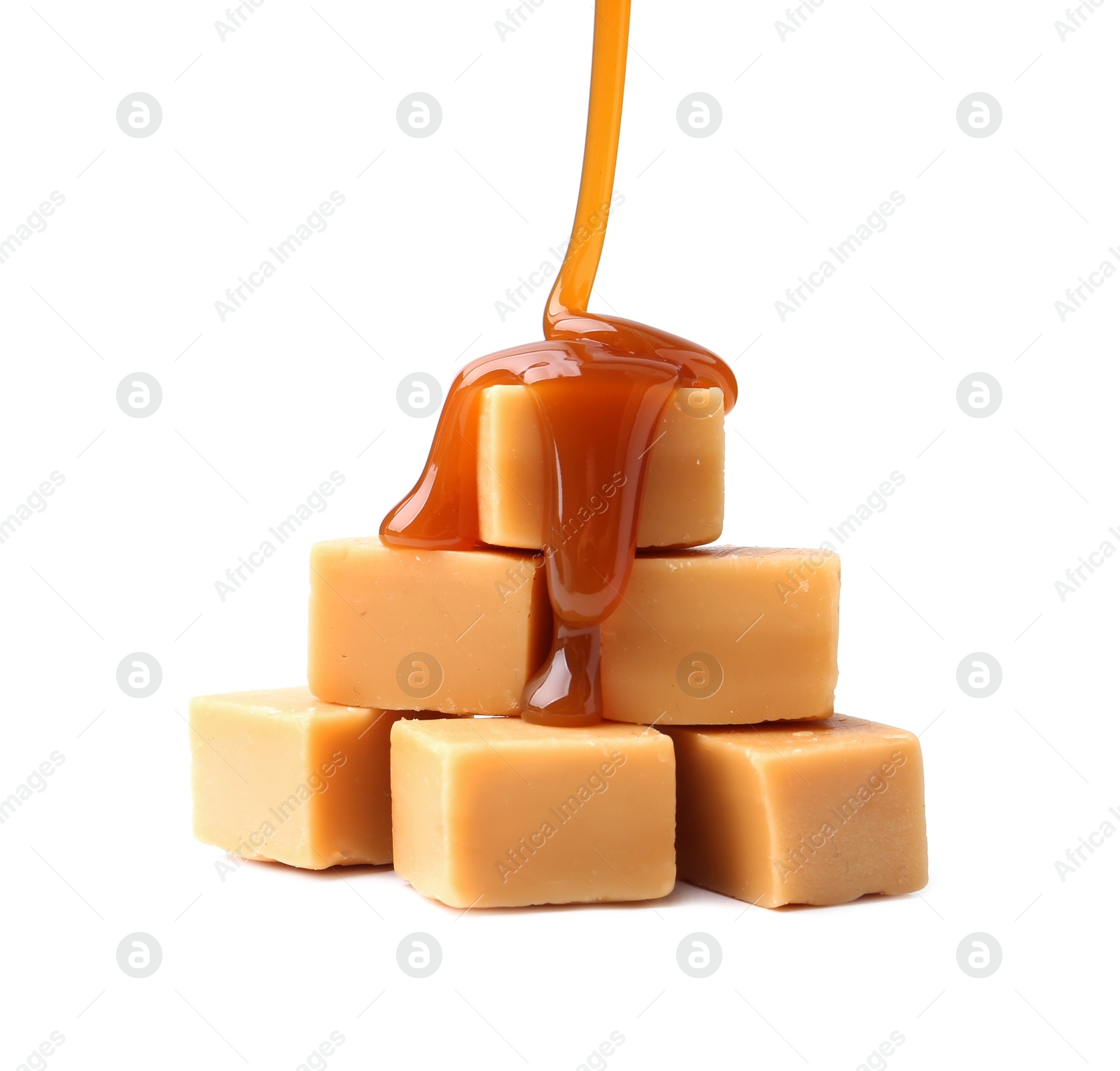 Photo of Caramel sauce dripping onto candies on white background, closeup