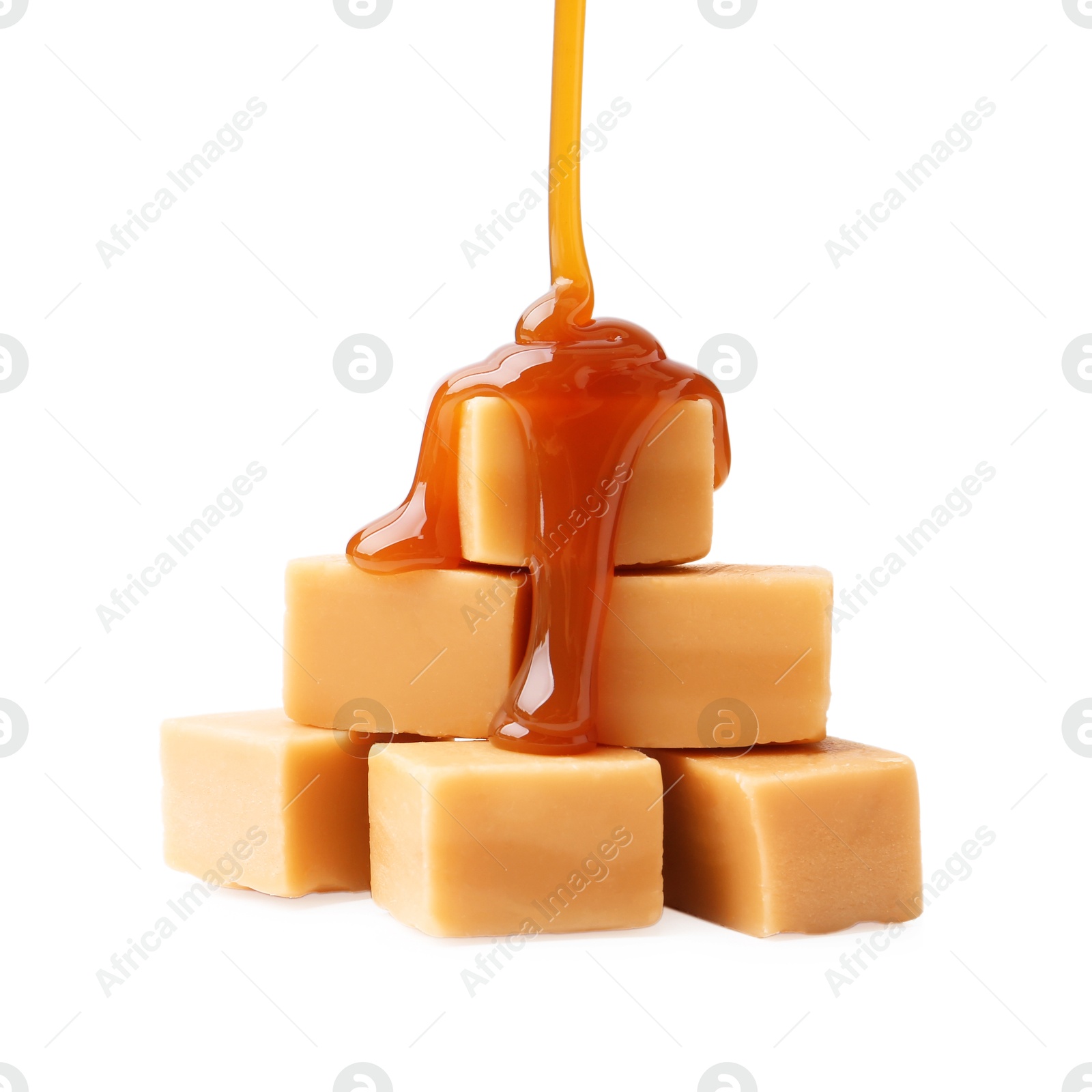 Photo of Caramel sauce dripping onto candies on white background, closeup