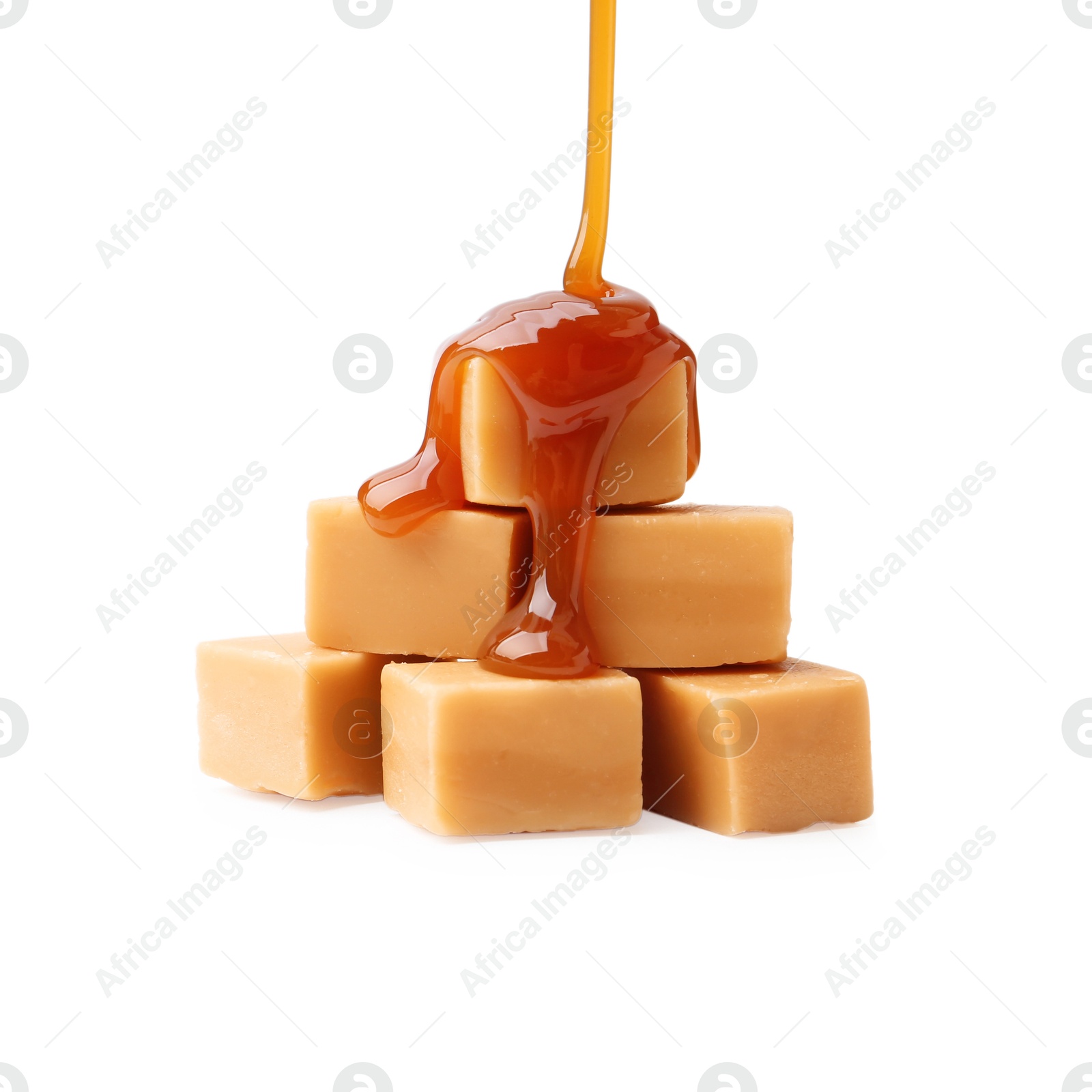 Photo of Caramel sauce dripping onto candies on white background, closeup