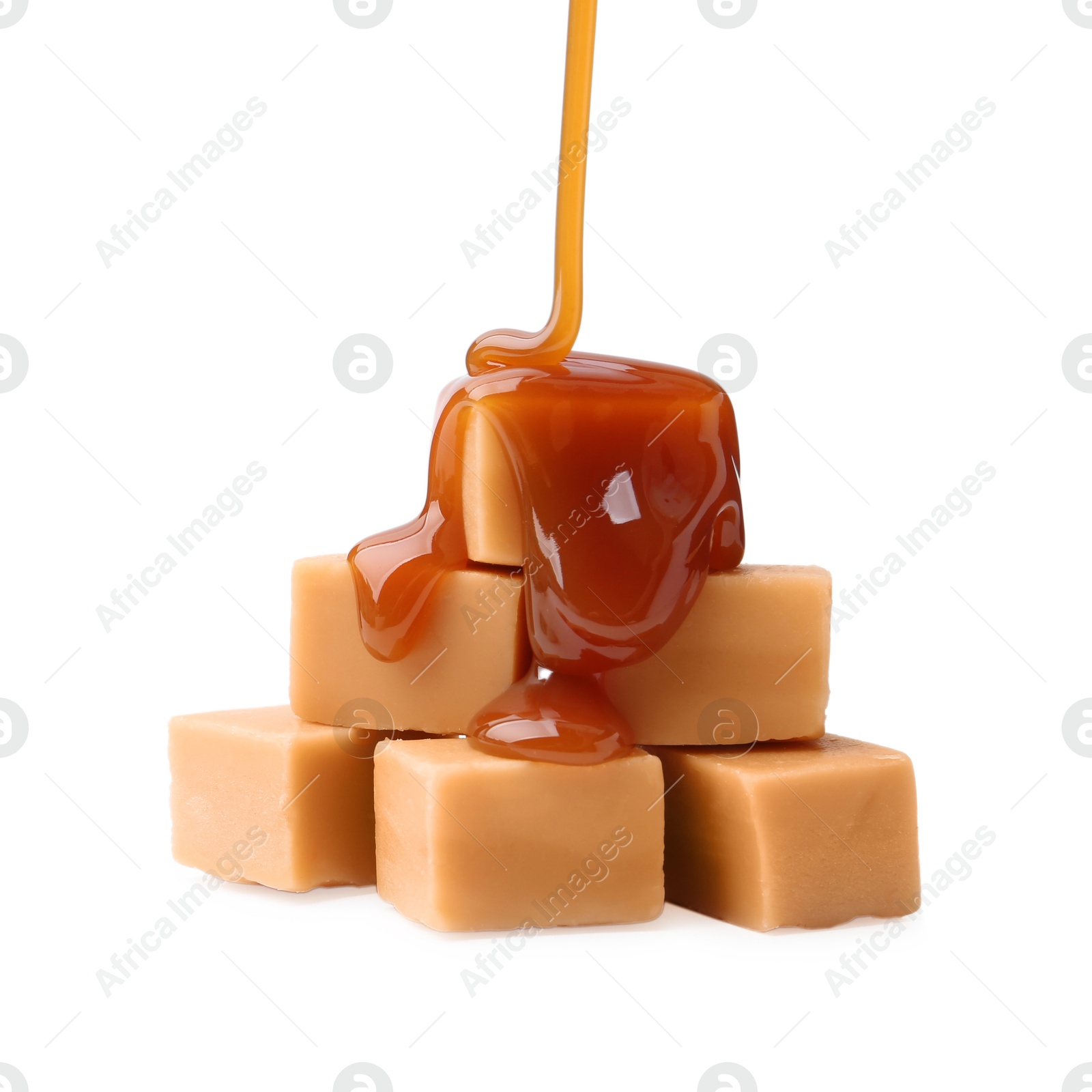 Photo of Caramel sauce dripping onto candies on white background, closeup