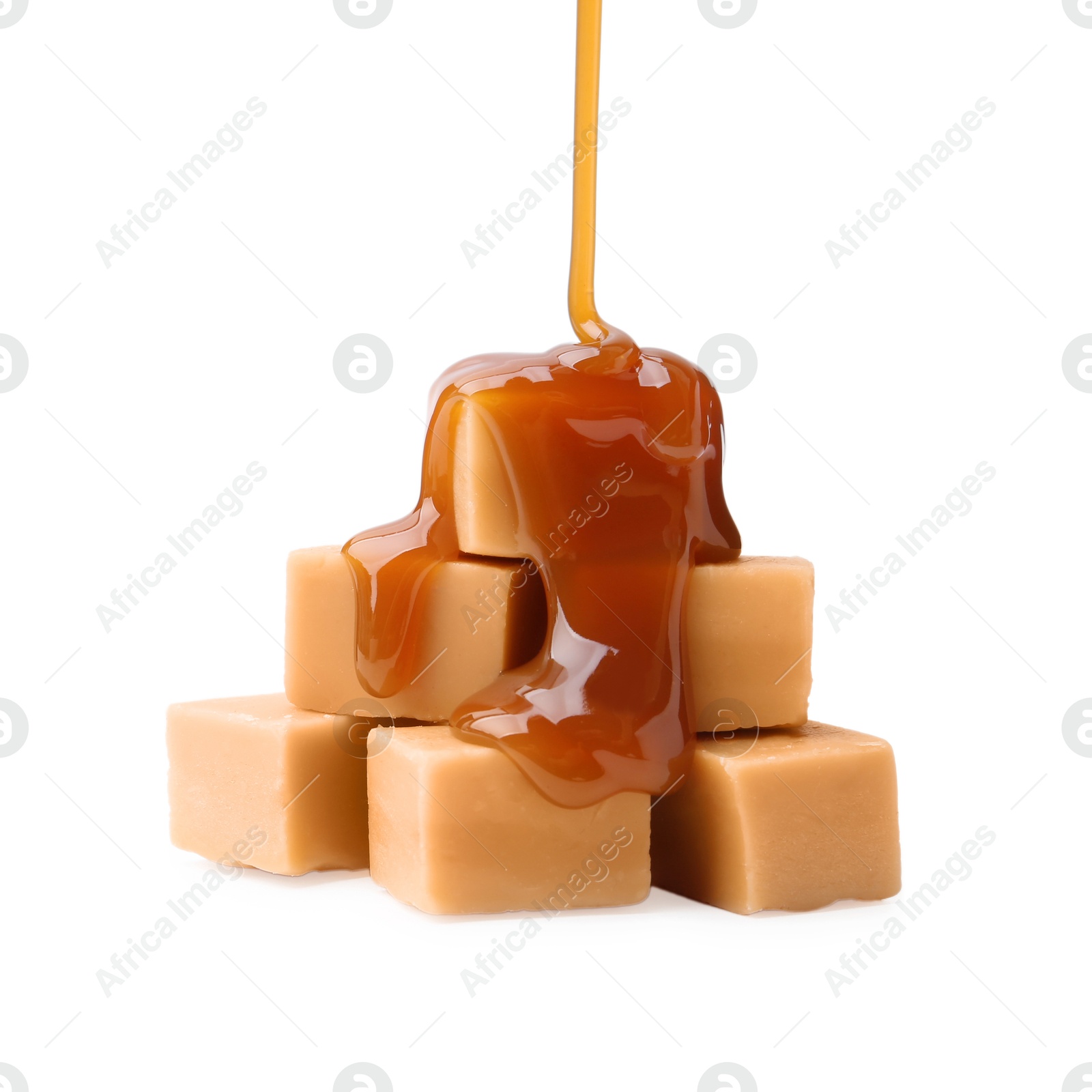 Photo of Caramel sauce dripping onto candies on white background, closeup