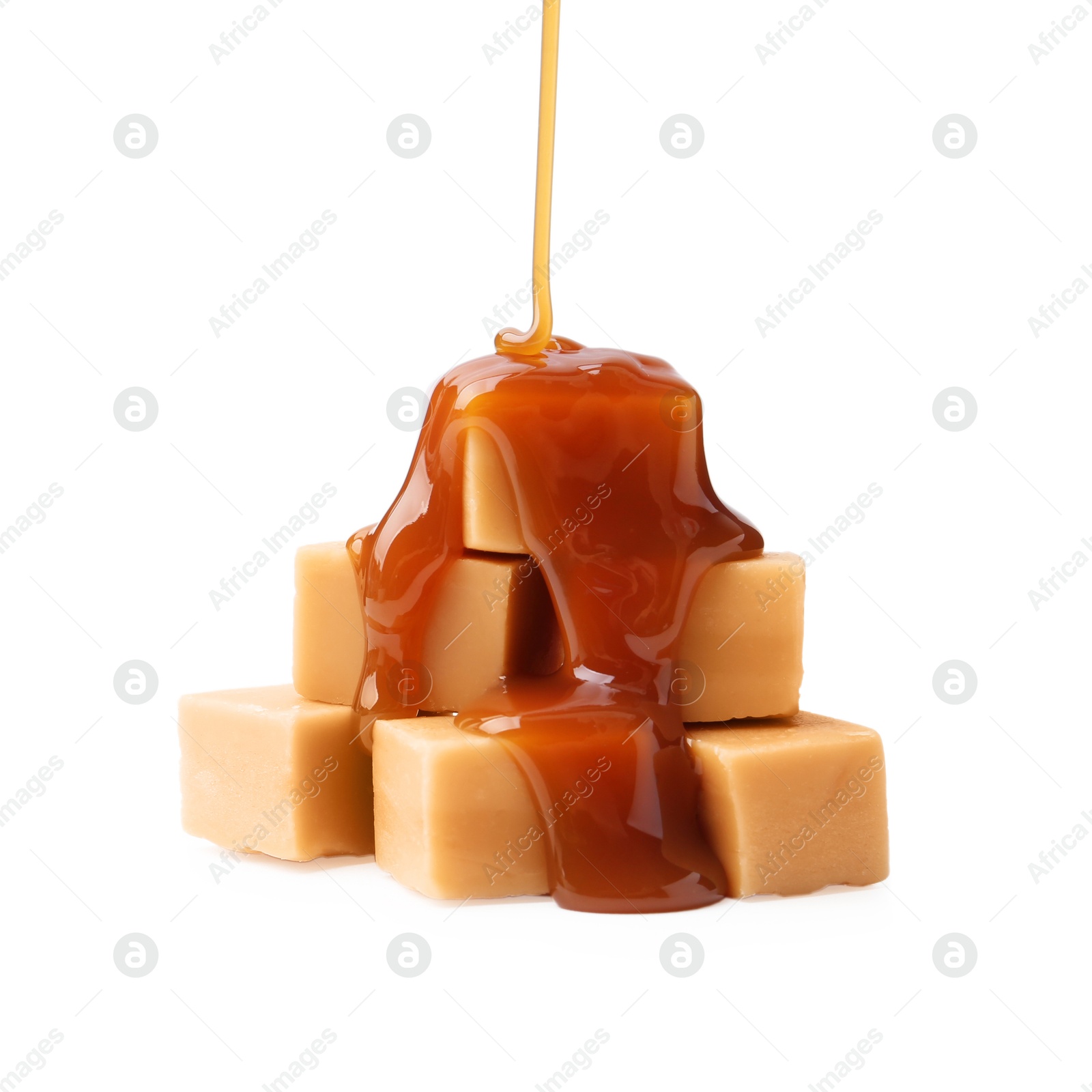 Photo of Caramel sauce dripping onto candies on white background, closeup