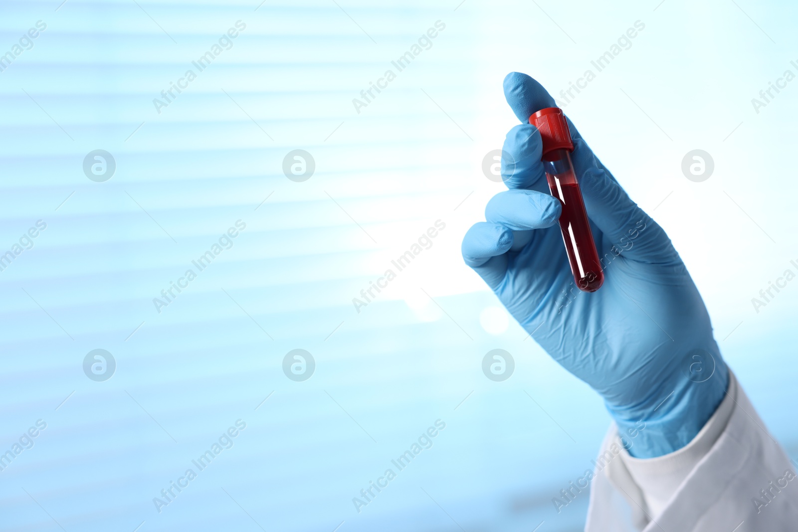 Photo of Laboratory testing. Doctor holding test tube with blood sample indoors, closeup. Space for text