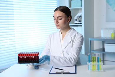 Laboratory testing. Doctor with blood samples at table indoors