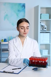 Laboratory testing. Doctor with blood samples at table indoors