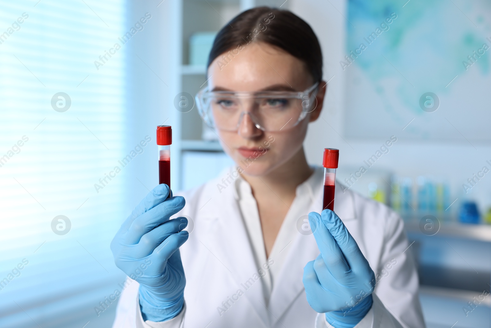 Photo of Laboratory testing. Doctor holding test tubes with blood samples indoors, selective focus