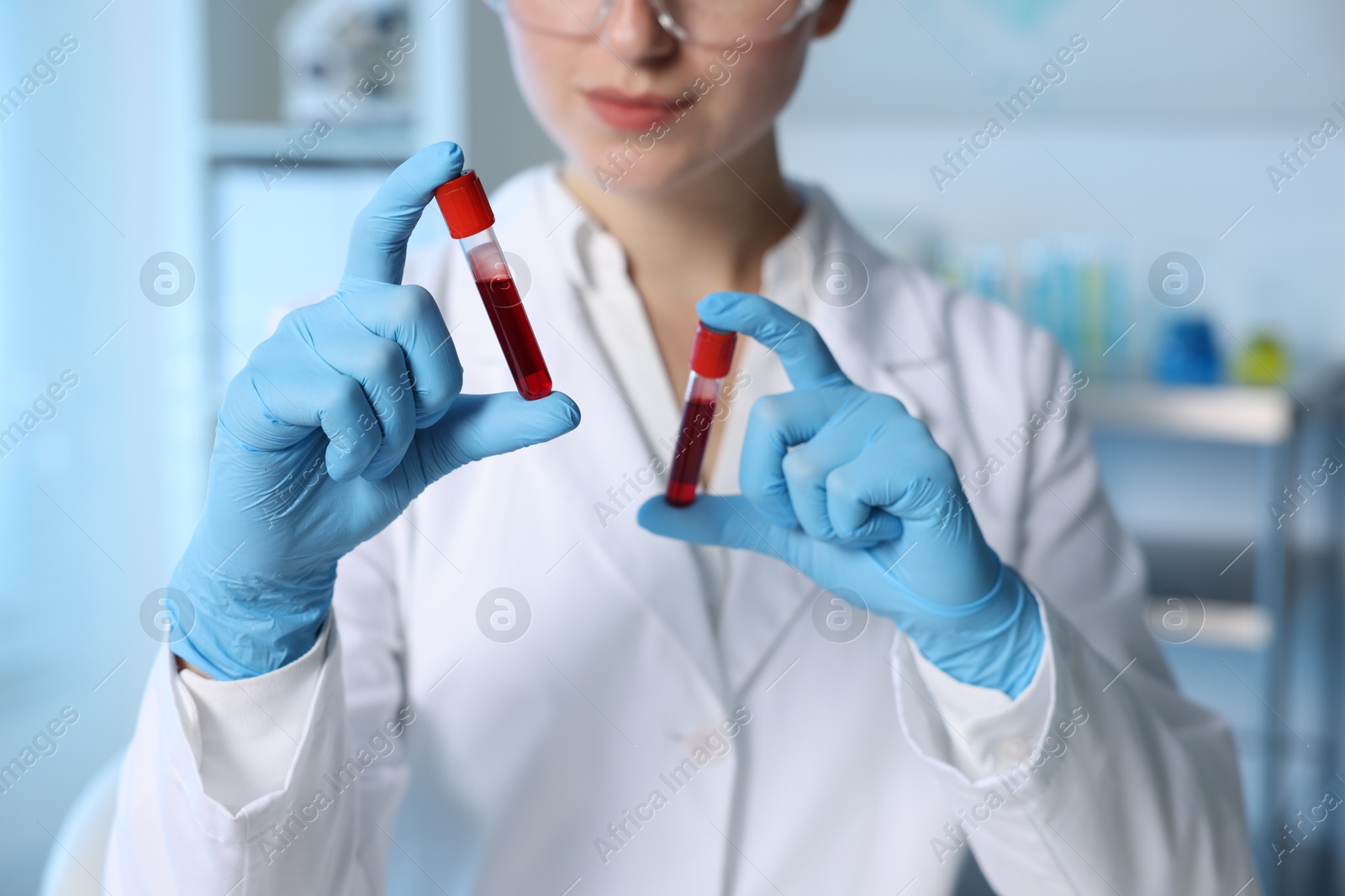 Photo of Laboratory testing. Doctor holding test tubes with blood samples indoors, closeup