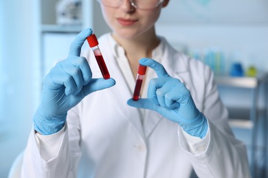 Laboratory testing. Doctor holding test tubes with blood samples indoors, closeup