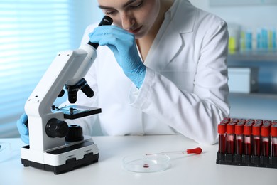 Laboratory testing. Doctor working with microscope at table indoors