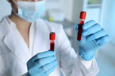 Laboratory testing. Doctor holding test tubes with blood samples indoors, closeup