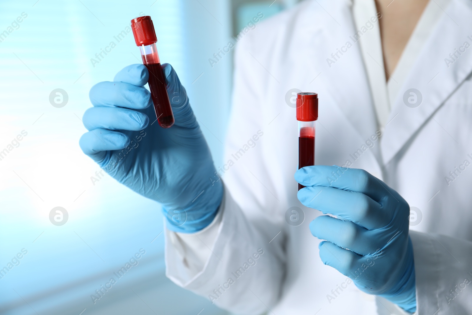 Photo of Laboratory testing. Doctor holding test tubes with blood samples indoors, closeup