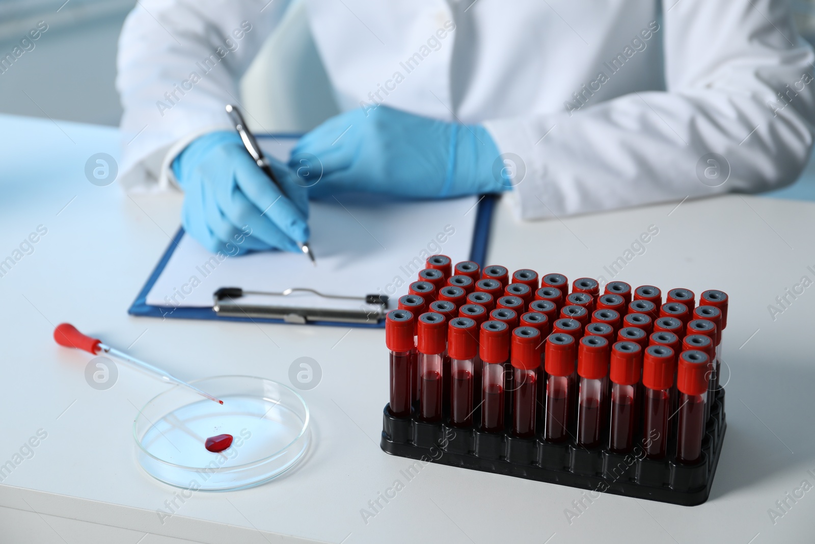 Photo of Laboratory testing. Doctor working at table with blood samples indoors, closeup