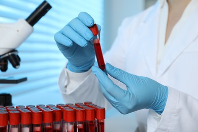 Photo of Laboratory testing. Doctor holding test tube with blood sample indoors, closeup