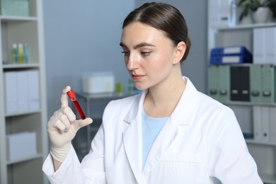 Photo of Laboratory testing. Doctor holding test tube with blood sample indoors