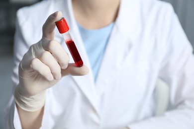 Laboratory testing. Doctor holding test tube with blood sample indoors, closeup