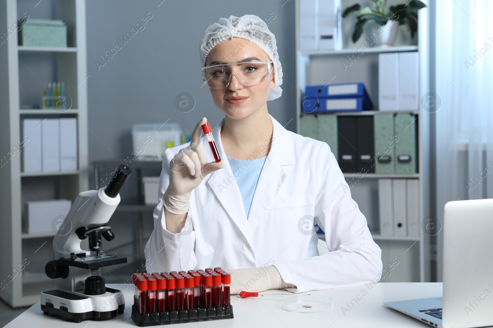 Photo of Laboratory testing. Doctor holding test tube with blood sample at table indoors