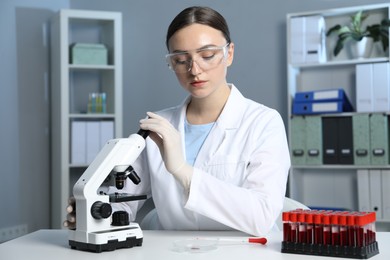 Laboratory testing. Doctor working with microscope at table indoors