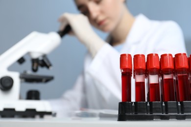 Photo of Laboratory testing. Doctor working with microscope at table indoors, focus on blood samples