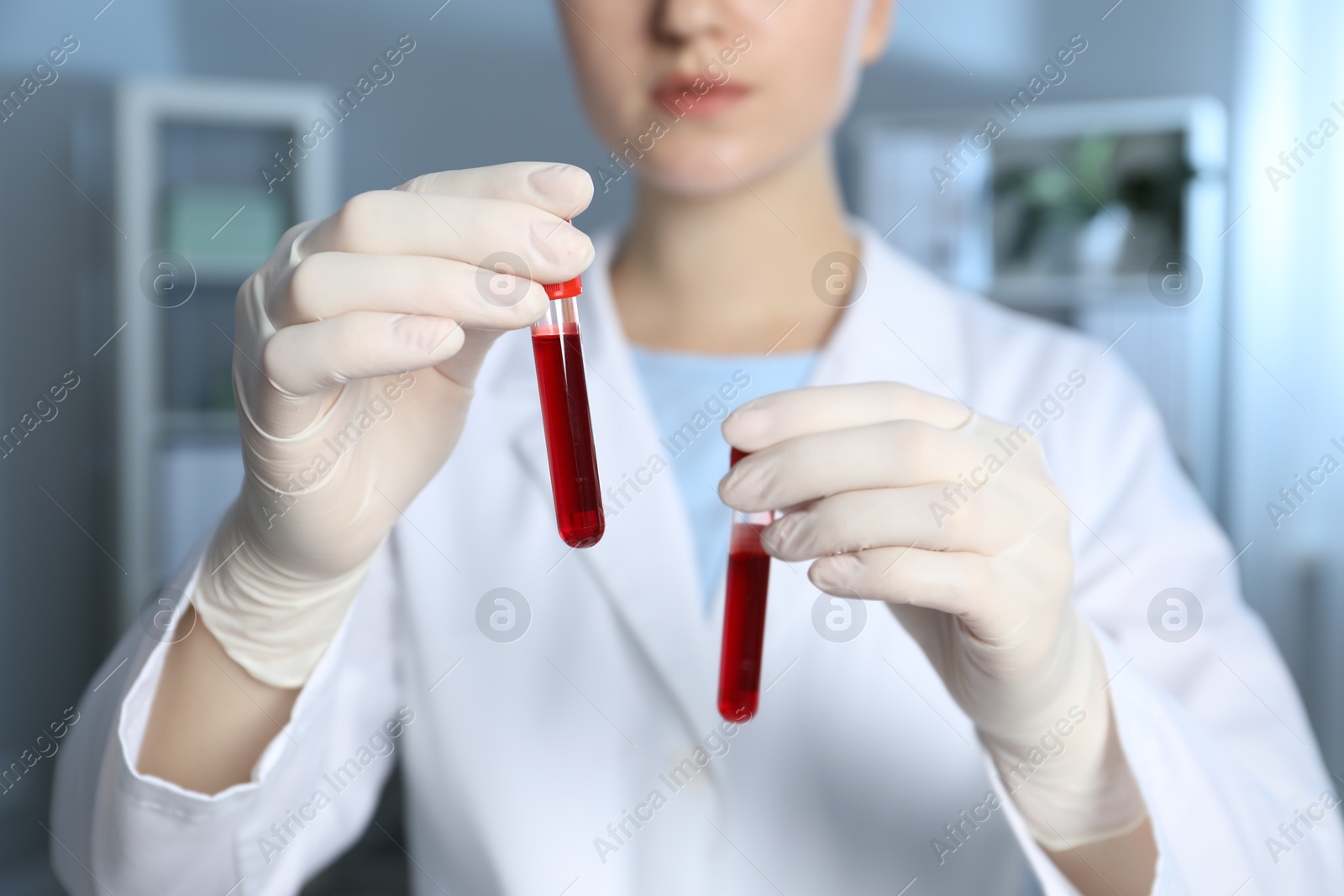 Photo of Laboratory testing. Doctor holding test tubes with blood samples indoors, closeup