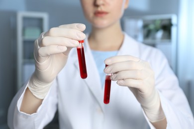 Photo of Laboratory testing. Doctor holding test tubes with blood samples indoors, closeup