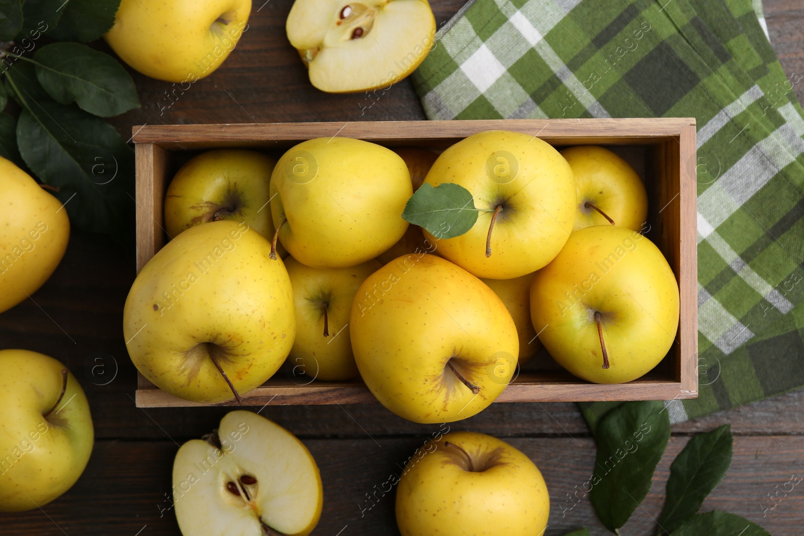 Photo of Ripe yellow apples in crate on wooden table, top view