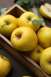 Photo of Ripe yellow apples in wooden crate on table, closeup