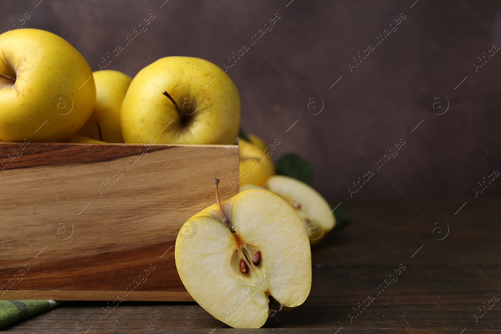 Photo of Ripe yellow apples in crate on wooden table, closeup. Space for text