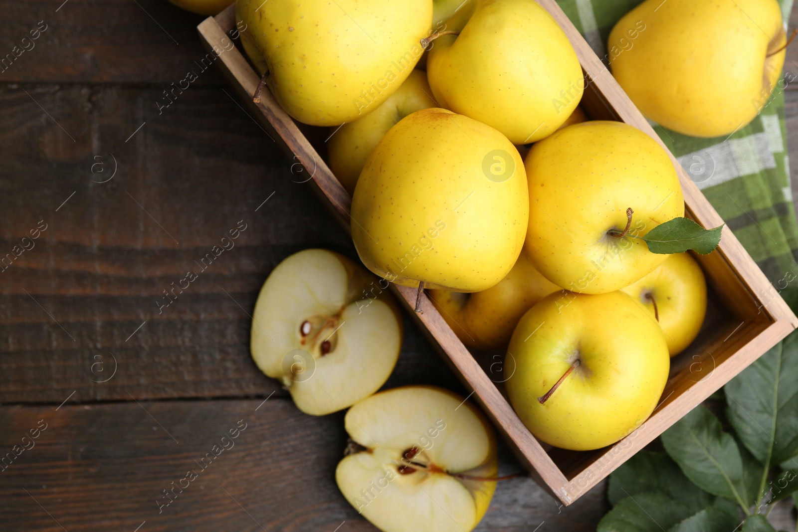 Photo of Ripe yellow apples in crate on wooden table, top view. Space for text